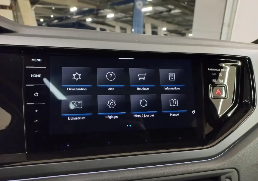 Écran tactile central du Volkswagen Taigo 2025, affichant le menu principal avec commandes digitales et bouton d’alerte.