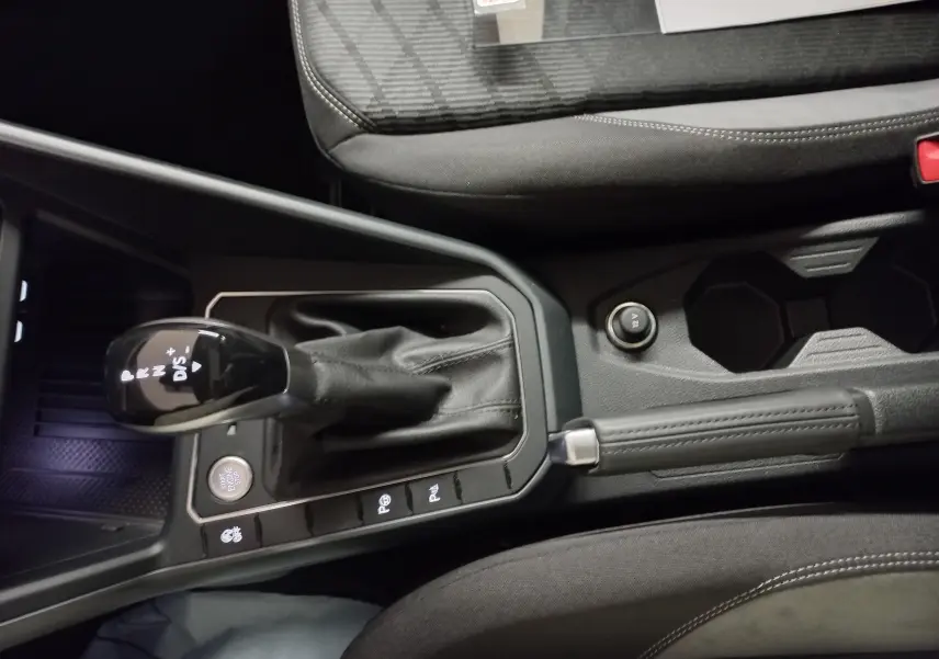 Vue rapprochée de la console centrale du Volkswagen Taigo blanc pur 2025, avec levier de vitesse automatique et frein à main.