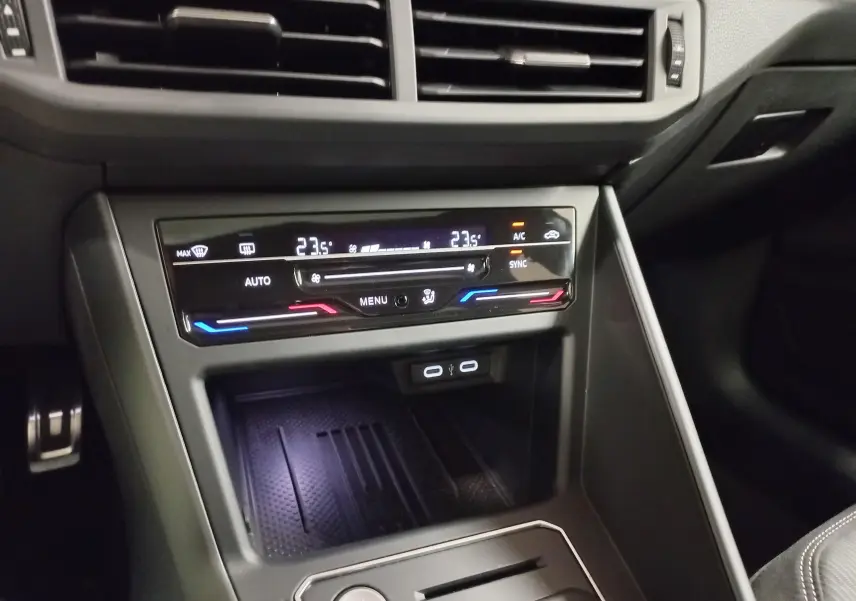 Vue rapprochée de la console centrale du Volkswagen Taigo blanc, avec commandes climatisation digitale et ports USB visibles.