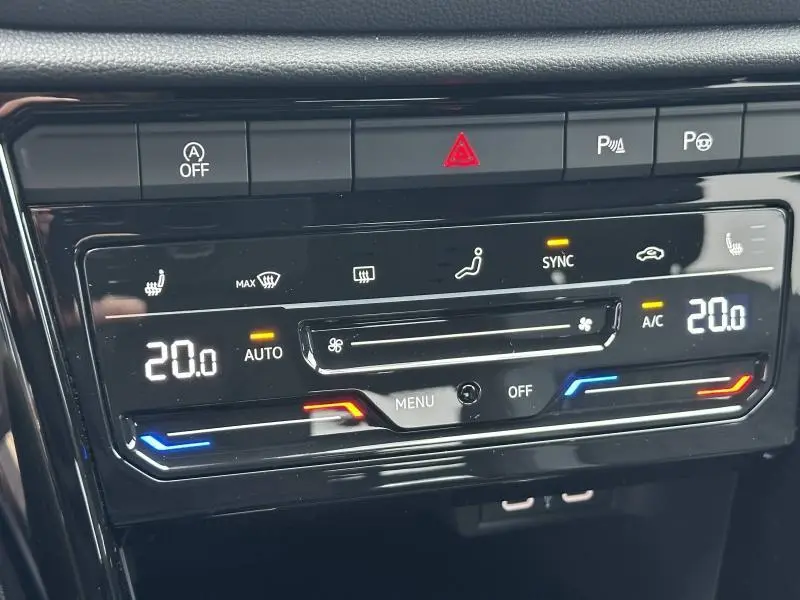 Gros plan sur la console de climatisation digitale du Volkswagen T-Roc 2025 avec réglages bi-zone à 20°C.