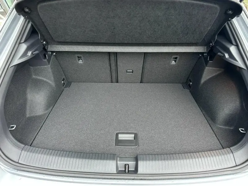 Coffre ouvert vu de l'arrière du Volkswagen T-Roc gris, montrant un espace de chargement propre et bien agencé.