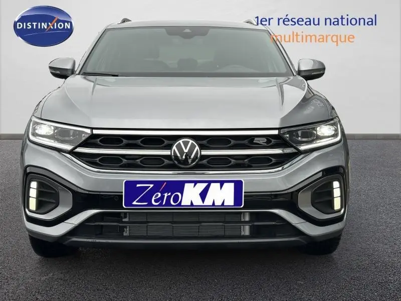 Vue frontale d'un Volkswagen T-Roc gris 2025 avec calandre R-Line et feux LED allumés.
