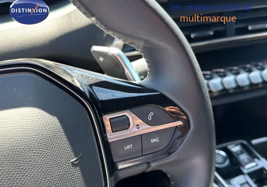 Gros plan sur le volant côté gauche du Peugeot 3008 Hybrid gris, avec commandes intégrées et palettes au volant visibles.