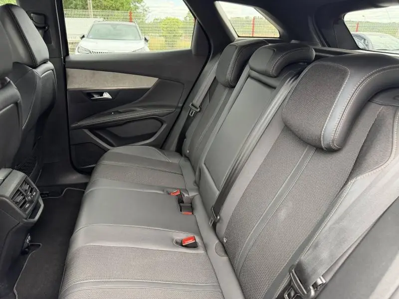 Vue intérieure de la banquette arrière du Peugeot 3008 2024, sièges en tissu et cuir gris avec ceintures de sécurité visibles.