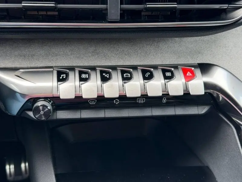 Gros plan sur la rangée de boutons métalliques du tableau de bord du Peugeot 3008 Gris Platinium, avec bouton alerte rouge.