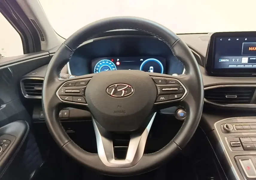 Vue intérieure centrée sur le volant cuir noir du Hyundai Santa Fe 2023 avec tableau de bord digital et écran tactile.
