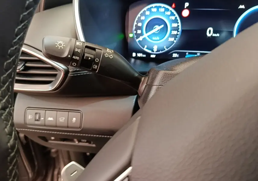 Gros plan sur le commodo gauche et le combiné d'instruments numérique du Hyundai Santa Fe gris foncé 2023.