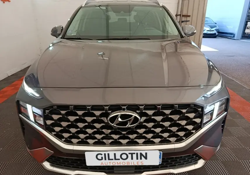 Vue avant d’un Hyundai Santa Fe gris foncé 2023 avec calandre imposante et phares LED allumés en intérieur.