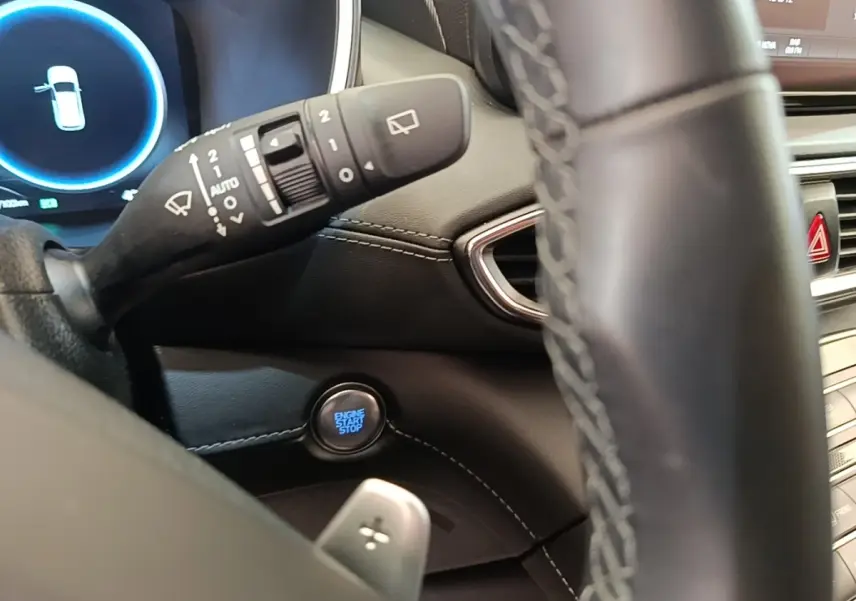 Gros plan sur le bouton start/stop et la commande d’essuie-glace, volant cuir partiellement visible, intérieur noir du Hyundai Santa Fe.