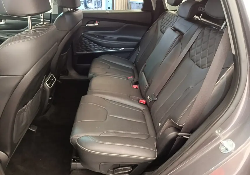 Vue intérieure côté droit des sièges arrière en cuir noir du Hyundai Santa Fe 2023 gris foncé, avec surpiqûres et ceintures visibles.