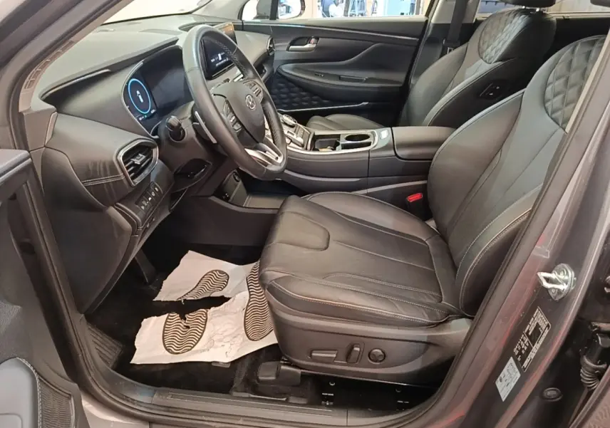 Vue intérieure côté conducteur du Hyundai Santa Fe 2023 gris foncé, sièges cuir noirs et tableau de bord moderne.