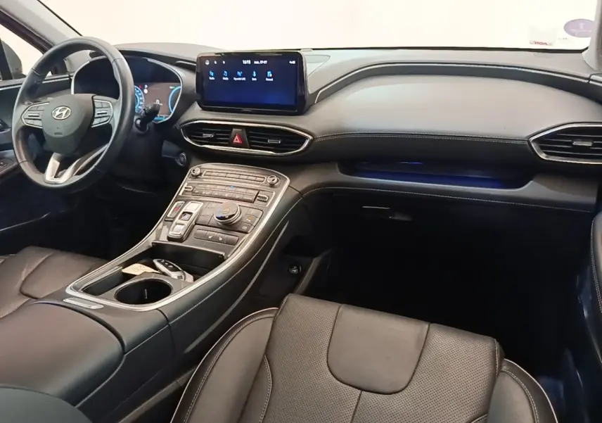 Vue intérieure côté passager du Hyundai Santa Fe 2023, tableau de bord noir avec écran tactile central et volant cuir.
