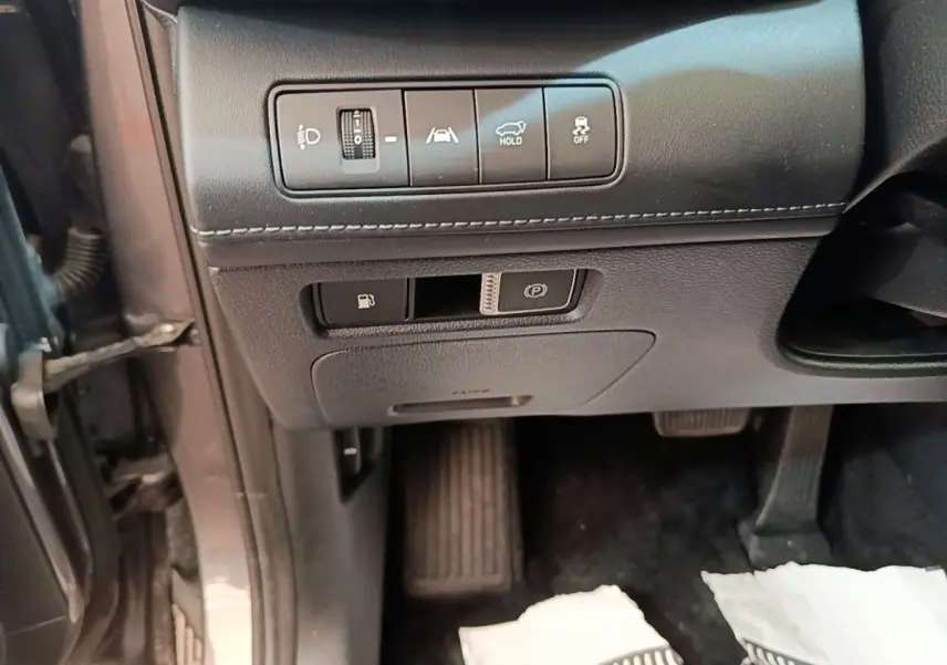 Détail intérieur côté conducteur du Hyundai Santa Fe gris foncé montrant les commandes d’aide à la conduite et frein de parking électrique.