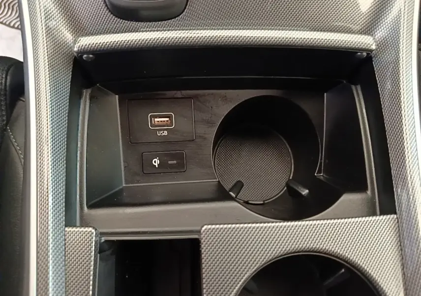 Gros plan sur la console centrale du Hyundai Santa Fe 2023, avec port USB, chargeur à induction et porte-gobelet.