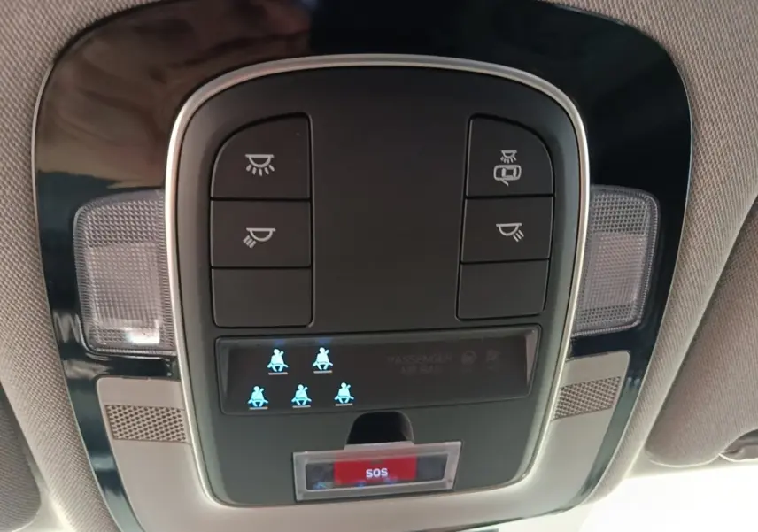Gros plan sur la console de toit intérieure du Hyundai Santa Fe gris foncé 2023 avec bouton SOS et voyants de ceinture allumés.