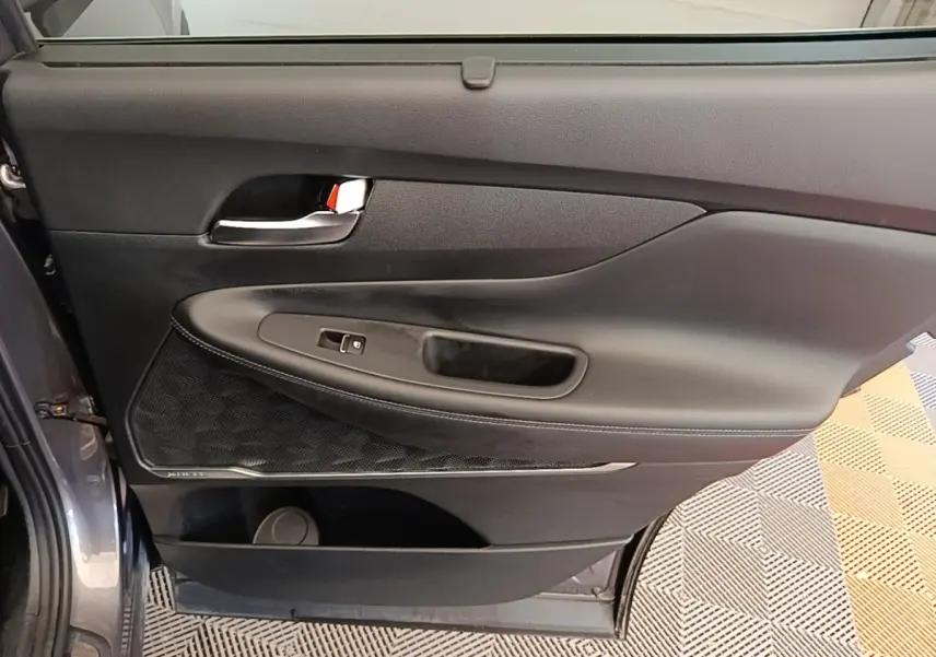 Vue intérieure côté gauche de la porte arrière gris foncé du Hyundai Santa Fe avec poignée chrome et commande de fenêtre.
