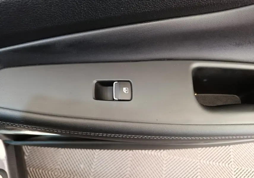 Gros plan sur la commande de verrouillage de porte intérieure noire du Hyundai Santa Fe gris foncé, côté conducteur.