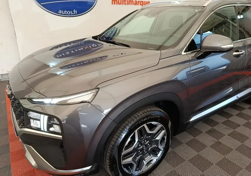 Vue 3/4 avant droit du Hyundai Santa Fe gris foncé 2023 avec jantes alliage et feux LED distinctifs.
