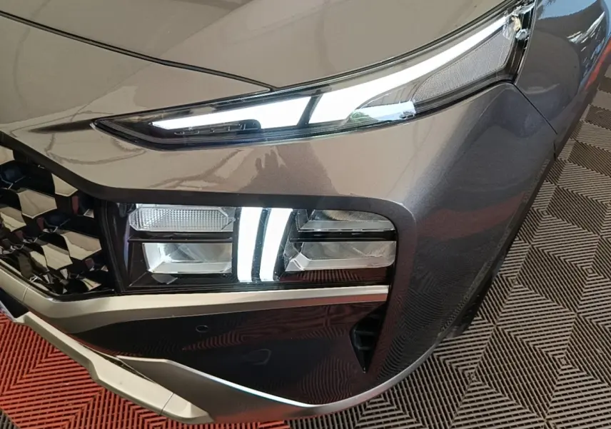 Gros plan sur l'avant droit gris foncé du Hyundai Santa Fe 2023, mettant en valeur ses phares LED et sa calandre distinctive.
