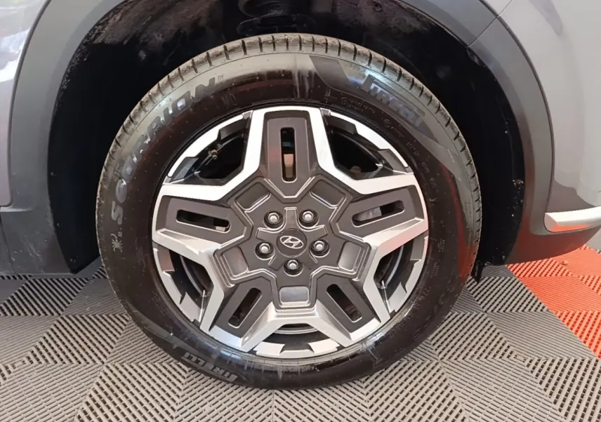 Gros plan sur la roue avant droite du Hyundai Santa Fe gris foncé, jante acier au design étoilé, pneu Pirelli Scorpion.