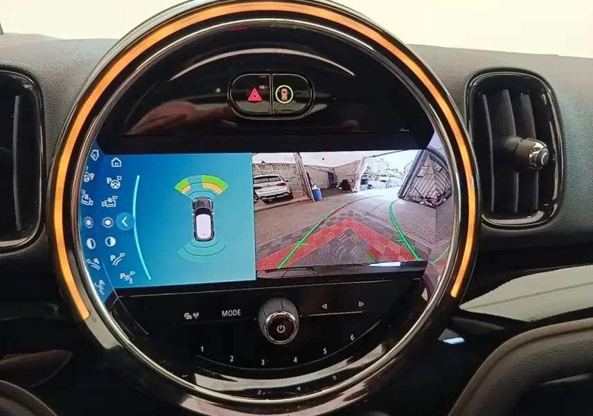 Vue rapprochée de l'écran tactile central rond du MINI Countryman 2023 affichant la caméra de recul et les capteurs de stationnement.