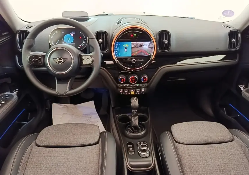 Intérieur avant du MINI Countryman 2023, vue tableau de bord et volant cuir noir avec écran tactile central lumineux.