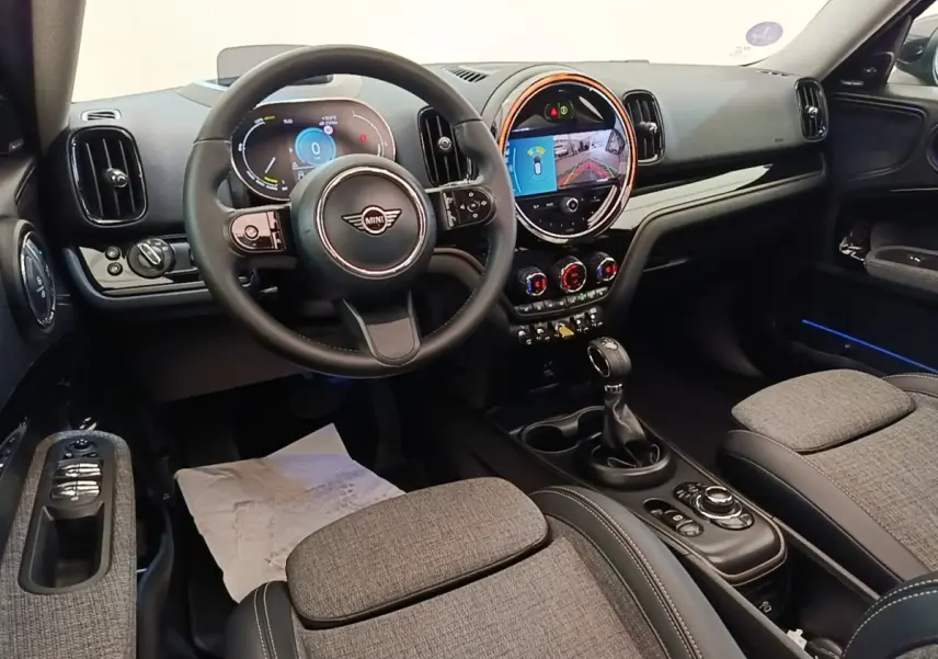 Vue intérieure avant du MINI Countryman Cooper SE avec volant cuir noir et écran tactile central lumineux.