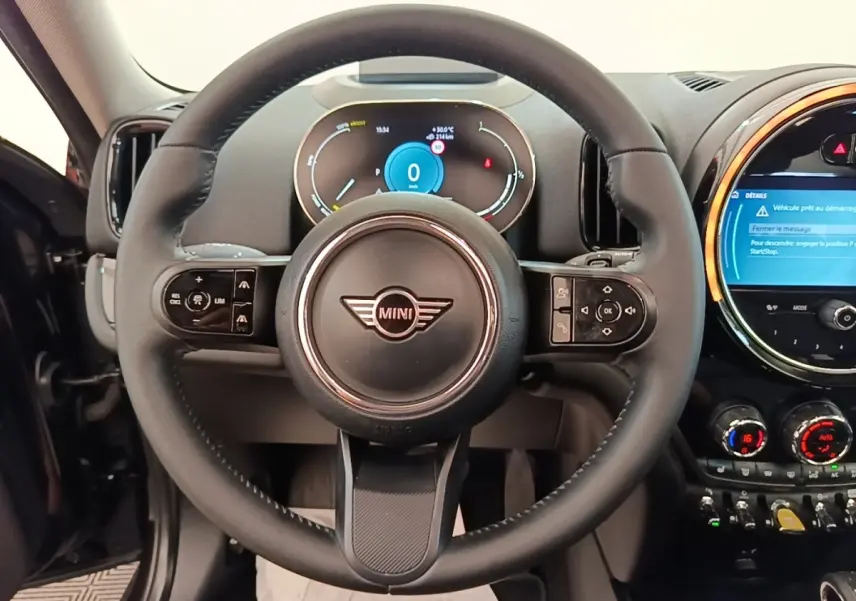 Vue intérieure centrée sur le volant cuir noir multifonctions du MINI Countryman 2023 avec tableau de bord numérique.