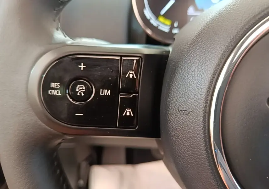 Gros plan sur les commandes de régulateur de vitesse au volant cuir noir du MINI Countryman hybride 2023.
