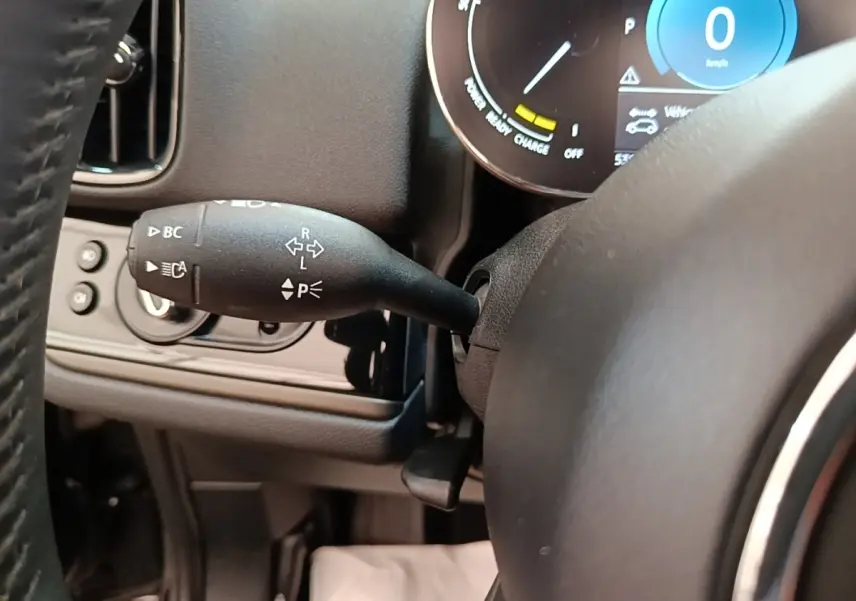 Gros plan sur la manette de clignotant noire à gauche du volant cuir dans l’habitacle du MINI Countryman noir 2023.