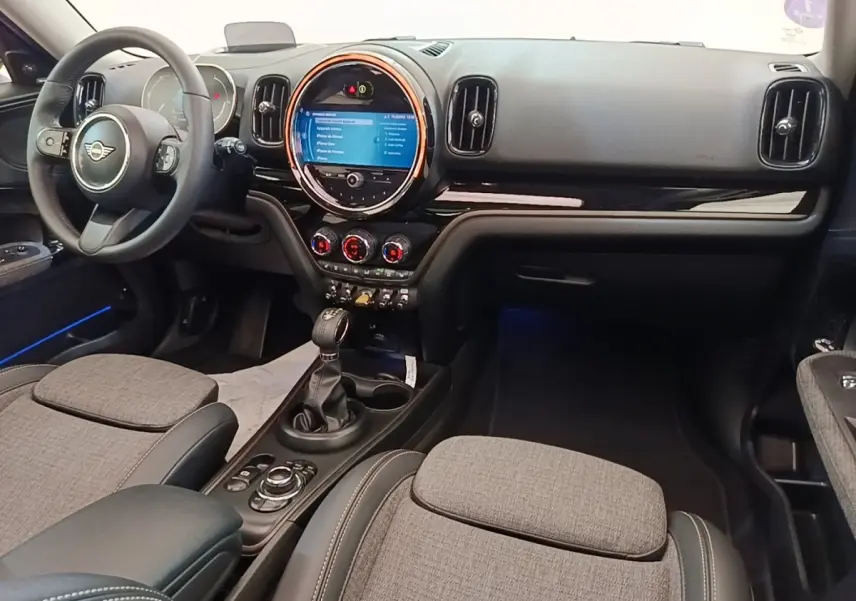 Vue intérieure avant droite du tableau de bord noir et gris du MINI Countryman Cooper SE avec écran tactile circulaire et volant cuir.