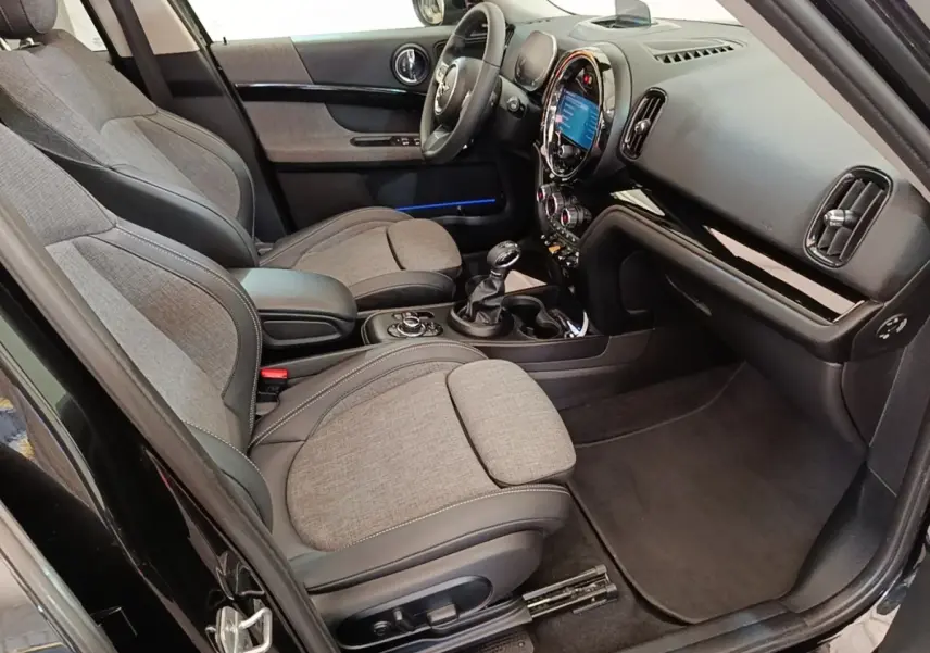 Vue intérieure côté conducteur du MINI Countryman noir 2023, sièges tissu et cuir, tableau de bord avec écran tactile.