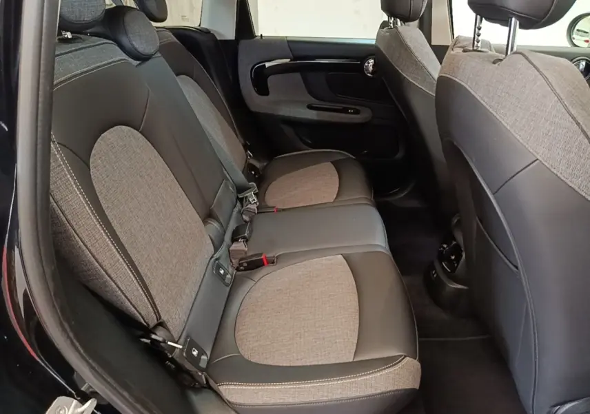 Vue intérieure côté gauche montrant la banquette arrière bi-matière tissu et cuir du MINI Countryman noir 2023.