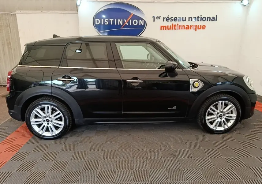 Profil côté gauche d'un MINI COUNTRYMAN Cooper SE hybride rechargeable noir, avec jantes argentées et logo ALL4 visible.
