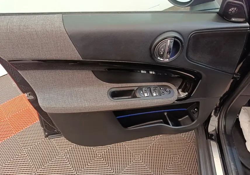 Vue rapprochée de la porte avant gauche noire du MINI COUNTRYMAN 2023 avec garniture tissu gris et commandes électriques.
