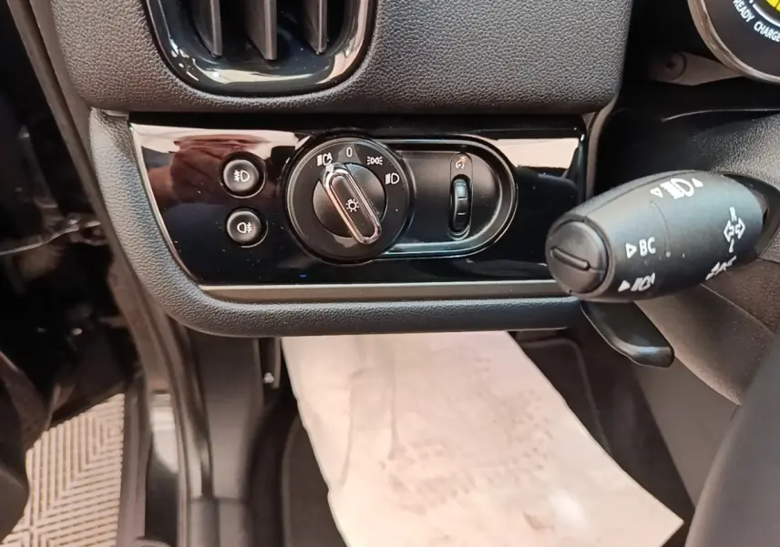 Gros plan sur les commandes d’éclairage et le commodo à gauche du volant dans l’habitacle noir du MINI Countryman 2023.