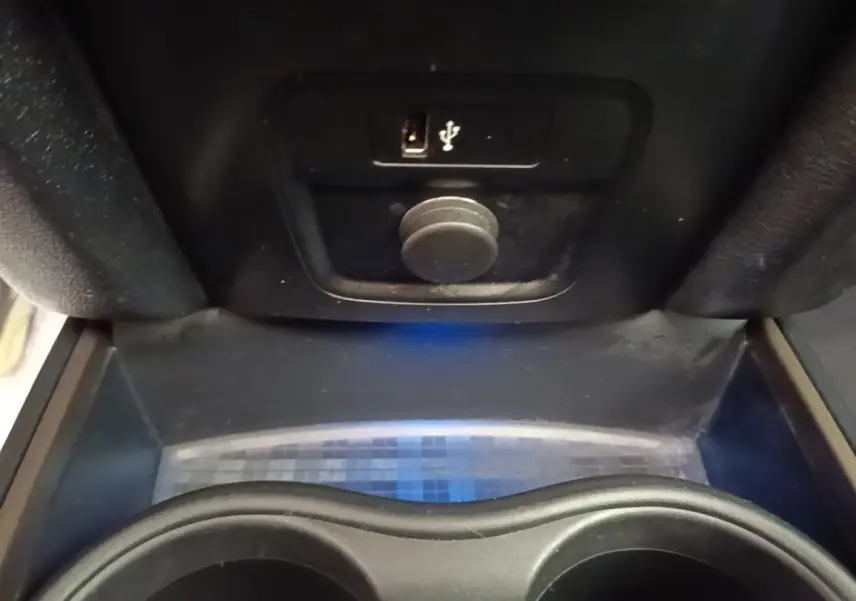 Gros plan sur la console centrale noire du MINI Countryman avec prise USB et prise 12V visibles.