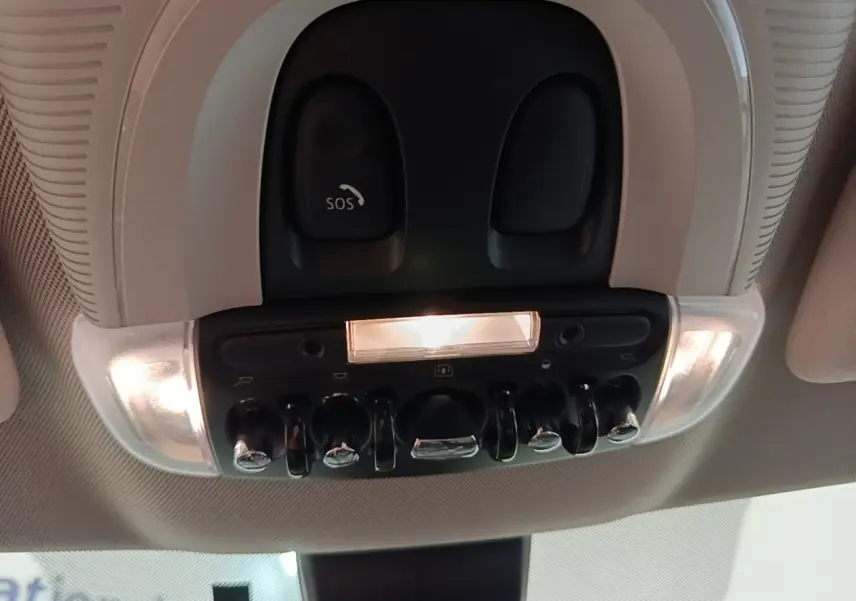 Vue intérieure en contre-plongée du plafonnier noir avec interrupteurs chromés et bouton SOS éclairé d'une MINI Countryman 2023.