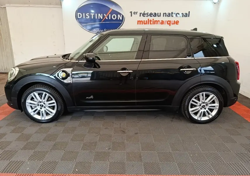 Profil côté gauche d’un MINI Countryman Cooper SE noir hybride rechargeable, avec jantes argentées et prise de charge visible.
