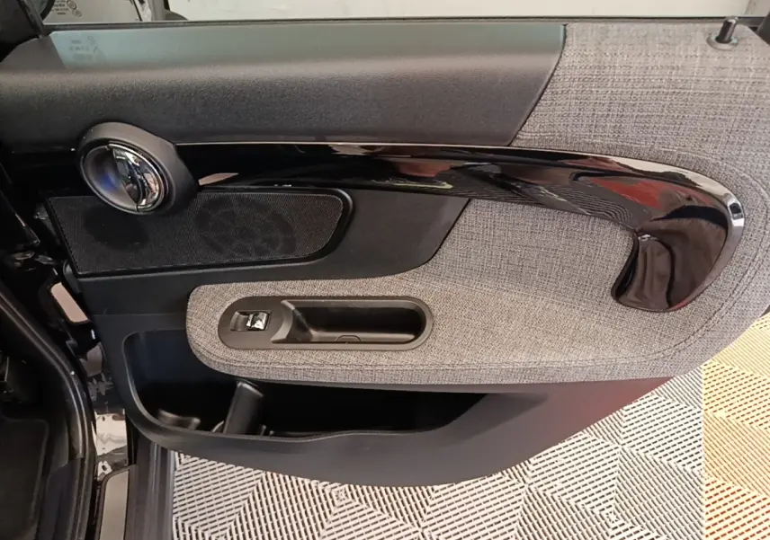 Détail de la porte avant gauche du MINI Countryman noir 2023 avec habillage tissu gris et poignée noire brillante.