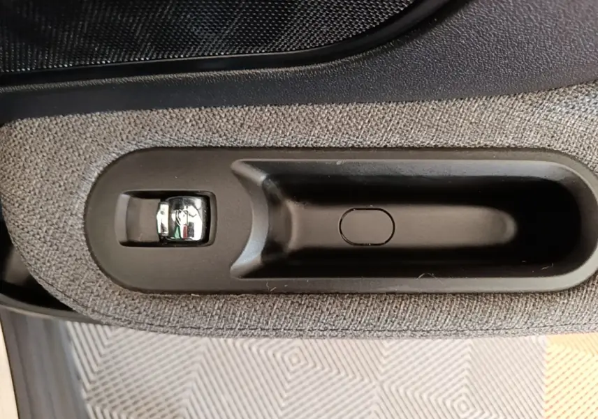 Gros plan sur la poignée intérieure noire et tissu gris clair de la porte côté conducteur du MINI Countryman noir 2023.