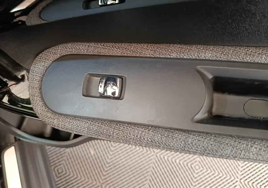 Gros plan sur la poignée intérieure de porte côté gauche du MINI Countryman noir, avec bouton de verrouillage chrome.