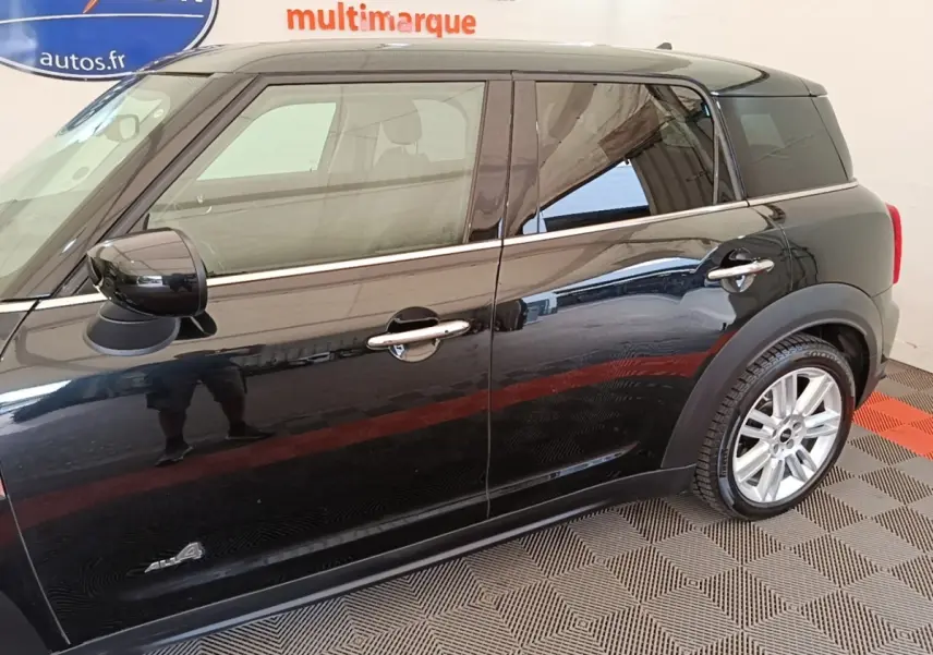 Vue latérale droite d'une MINI Countryman noire avec jantes argentées et rétroviseurs noirs brillants.