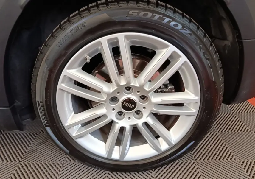 Gros plan sur la roue avant gauche du MINI Countryman noir, jante alliage argentée et pneu hiver Pirelli.