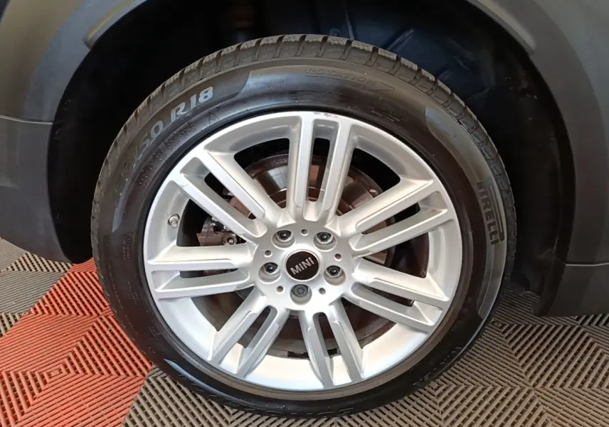Gros plan sur la roue avant droite du MINI Countryman noir, mettant en valeur la jante alliage argentée et le pneu Pirelli.