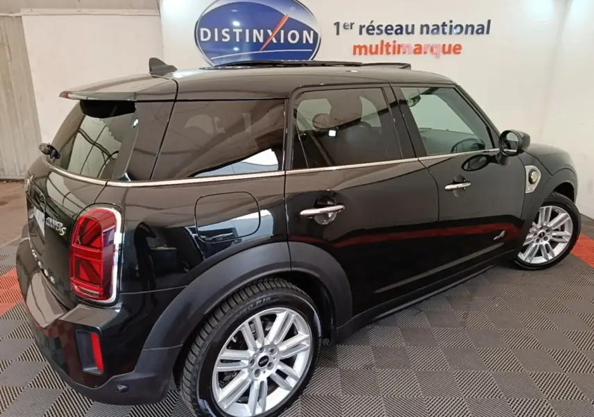 Vue 3/4 arrière droite d'une MINI Countryman noire avec jantes argentées dans un showroom intérieur.