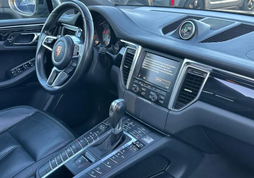Intérieur noir du Porsche Macan Diesel 2015 vu côté conducteur, avec volant cuir multifonctions et console centrale.