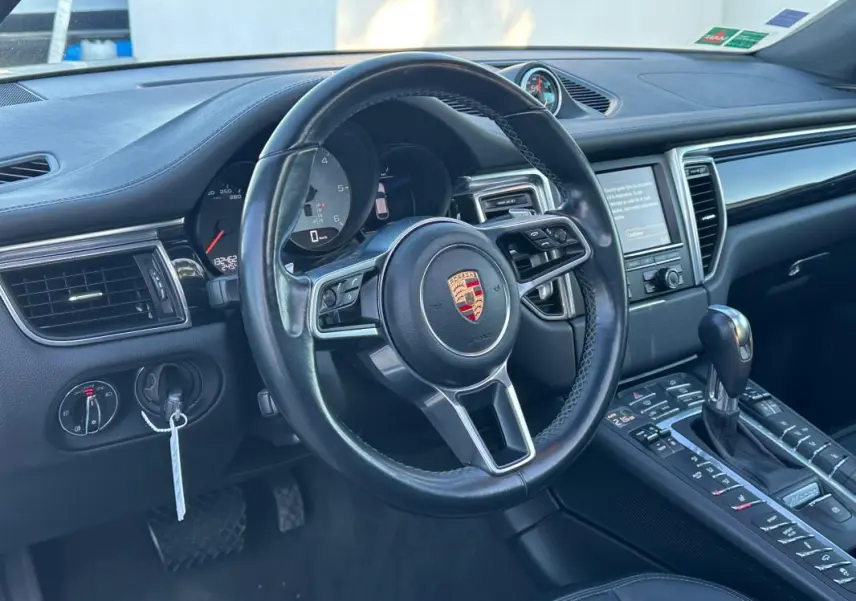Intérieur noir du Porsche Macan 2015 vu côté conducteur, volant cuir multifonctions et console centrale avec levier de vitesse.