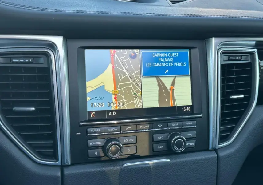 Vue rapprochée de l’écran de navigation central du tableau de bord du Porsche Macan gris foncé de 2015.