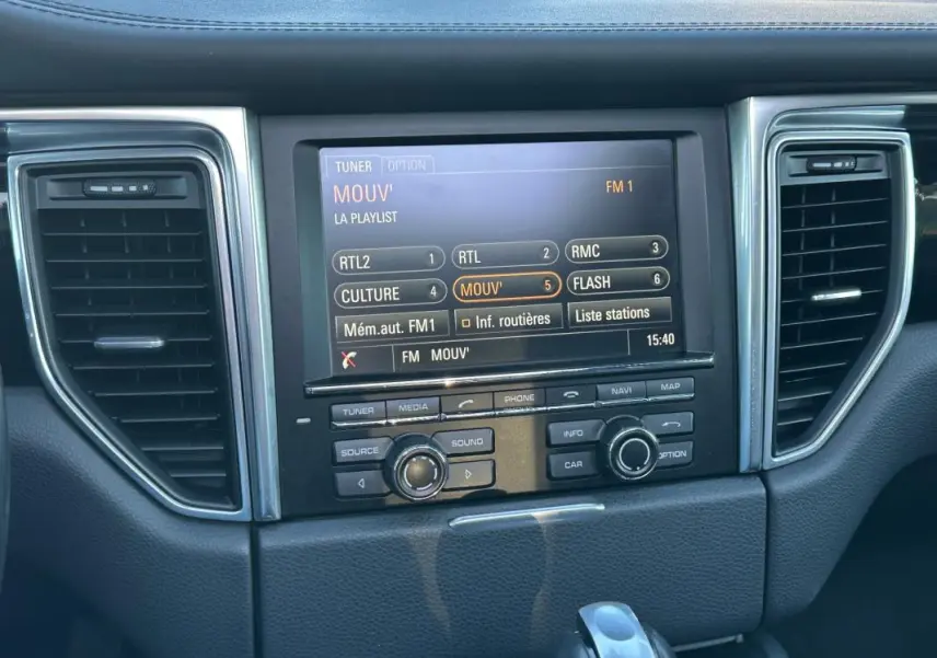 Vue rapprochée de la console centrale du Porsche Macan 2015 avec écran multimédia et commandes intégrées.
